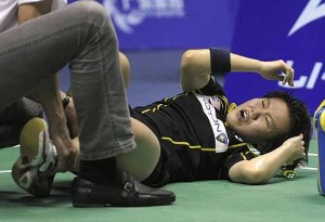 Painful end: Julia Wong grimacing while receiving treatment for a knee injury during Monday's match against Yip Pui Yin of Hong Kong.The shuttler returned home Tuesday (below) and was whisked to the hospital for medical tests on the extent of the injury.