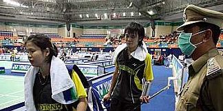 Masked protector: Malaysia&rsquo;s Sabrina Chong and Ong Jien Guo walking past a masked security personnel after losing to Chinese mixed doubles pair He Hanbin-Yu Yang yesterday.