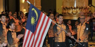 Al Amin hands the Malaysian flag to Lee Chong Wei. (photo: AFP)