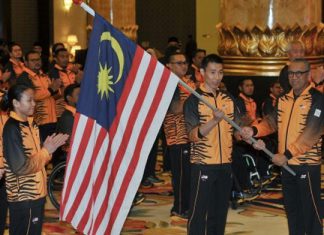 Al Amin hands the Malaysian flag to Lee Chong Wei. (photo: AFP)