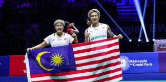 Chen Tang Jie and Toh Ee Wei proudly holding the Malaysian flag after winning the gold medal at the 2025 Badminton World Championships. (Photo: AFP)